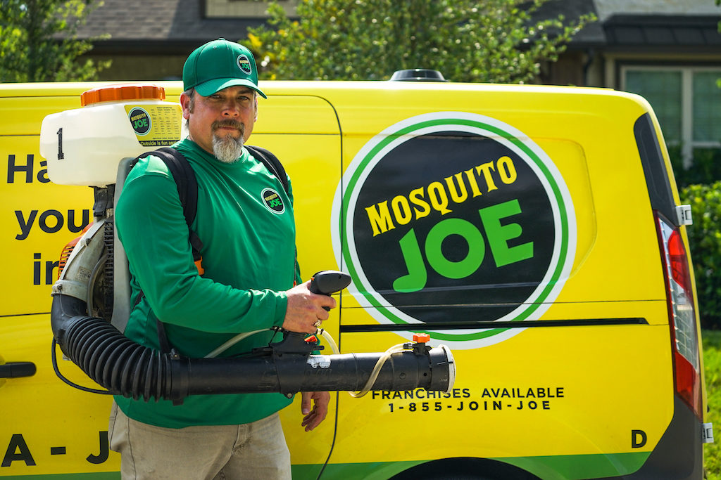 Mosquito Joe of Technician posing for photo next to yellow Service Van